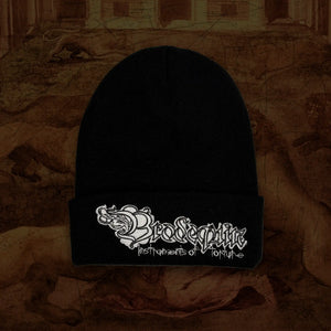 A black knit beanie with a silver embroidered band logo reading 'Brodequin Instruments of Torture' on the front cuff, displayed against a dark, textured brown background.