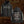 Front and back views of a black Liturgy band hoodie with gothic white text and red geometric line art, displayed against a textured brown background.