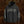 A black Liturgy band hoodie with white gothic-style text graphics on the chest, left sleeve, and right sleeve, displayed against a textured brown background.