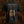A black short-sleeve Brodequin band t-shirt shown from the back, featuring an elaborate gold-colored gothic design with text, a central crest, and decorative script, set against a dark textured background.